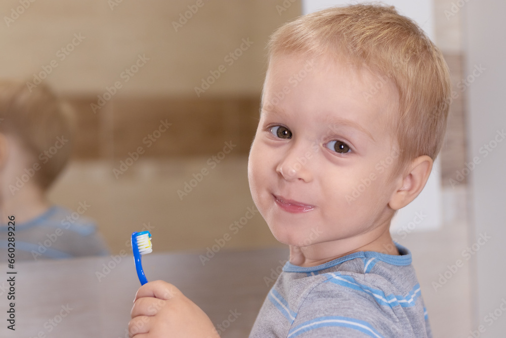 Little boy brushing his teeth in the bathroom. Child with a toothbrush in the bathroom. Child looking at the camera Little boy brushing his teeth in the bathroom. Child with a toothbrush in the bathroom. Child looking at the camera