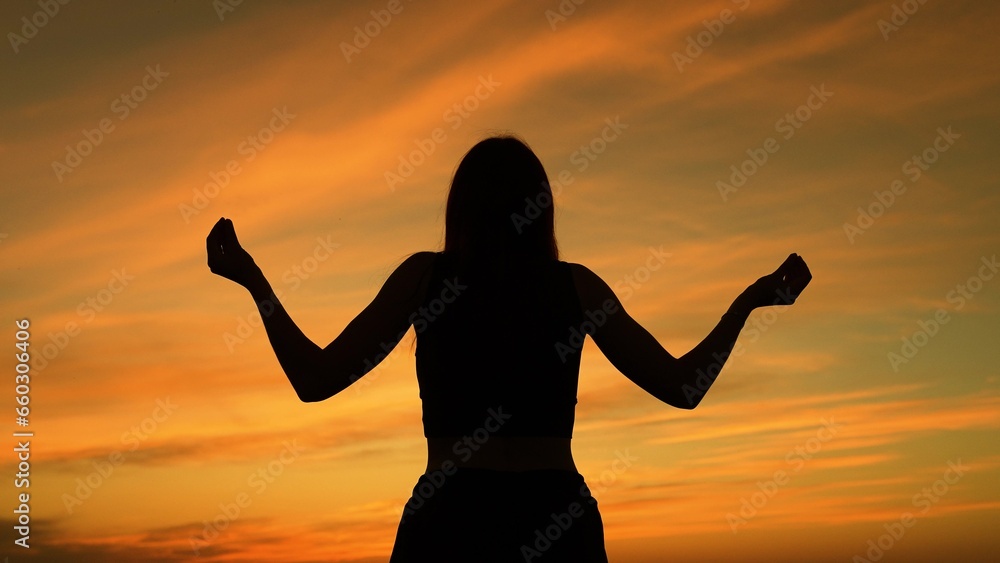 Calm woman meditating at sunset dark silhouette spiritual practice outdoors