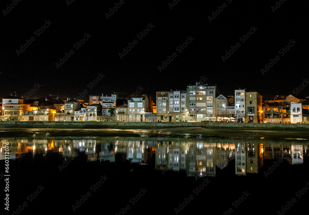 Night view of the Bouzas neighborhood in the city of Vigo. The buildings are reflected in the sea. Rías Baixas, Galicia, Spain.