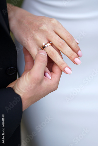 During the wedding ceremony  the groom puts a wedding ring on the bride s finger. Wedding traditions.