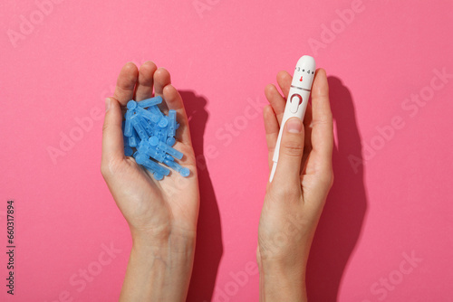 Medical equipment for diabetics in hands on pink background, top view