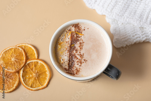 A cup of warm cocoa with a dry orange and cozy plaid flat lay. Warm drink top view