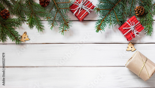 Spruce tree branches, presents, and pine cones arranged on a white wooden rustic surface. Top-down view with space for text. Ideal for banners and backgrounds