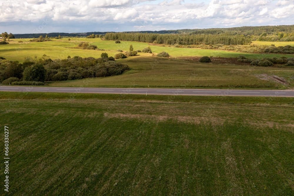 Drone photography or rural road going through meadows and forest