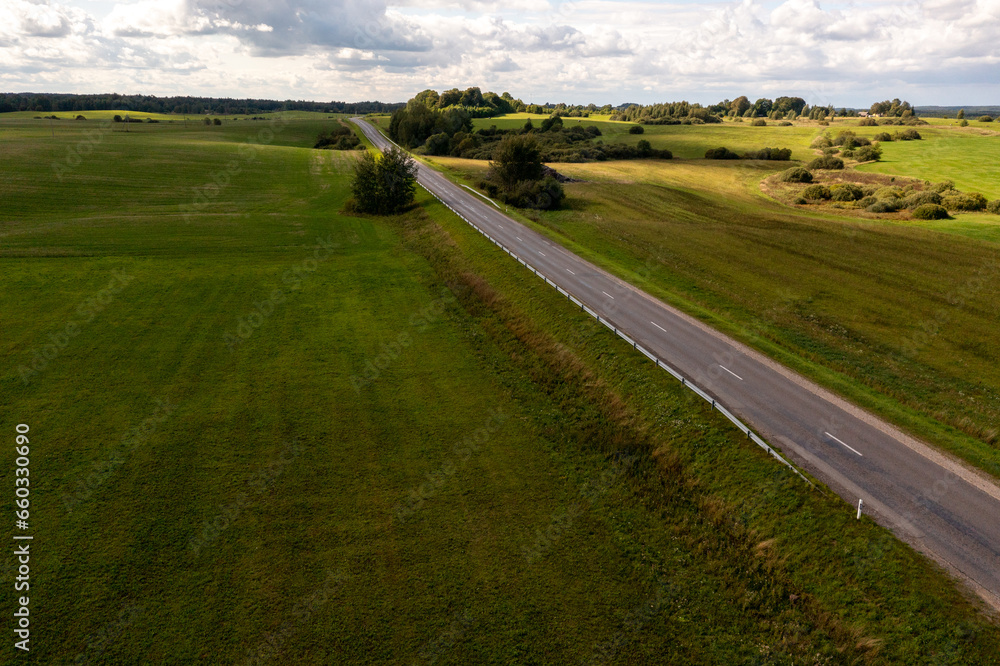 Drone photography or rural road going through meadows and forest