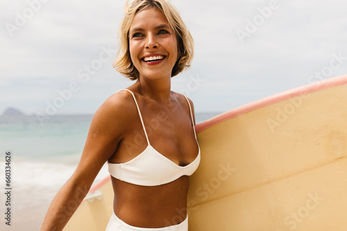 Happy woman enjoying summer surfing adventure on the beach