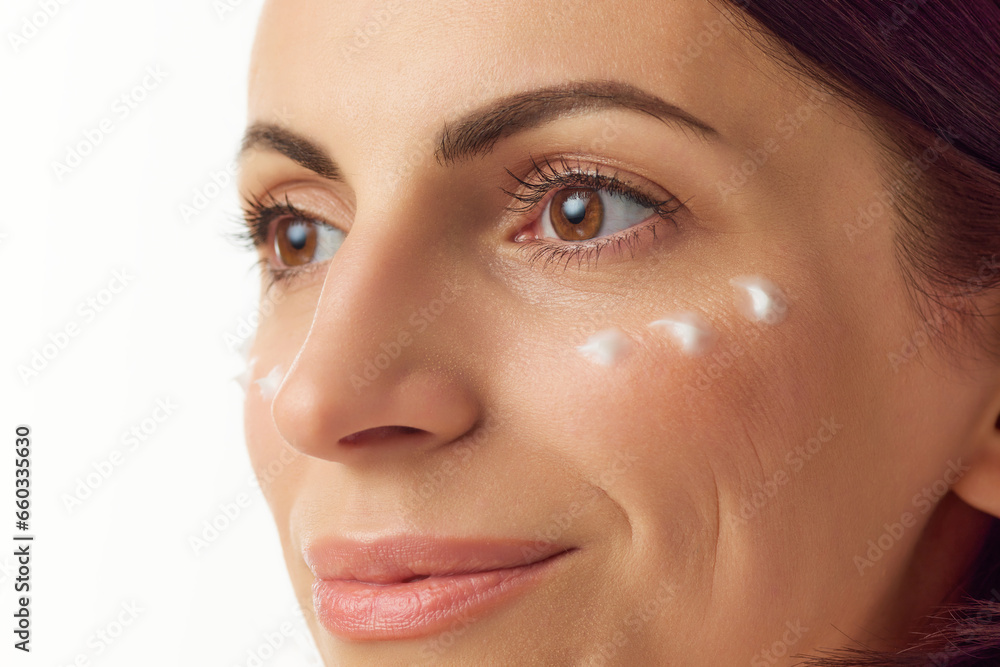 Closeup portrait. Smiling young beautiful woman with well-kept skin and cream swatches isolated over white background. Natural beauty, skincare, cosmetology. Closeup portrait. Smiling young beautiful woman with well-kept skin and cream swatches isolated over white background. Natural beauty, skincare, cosmetology.