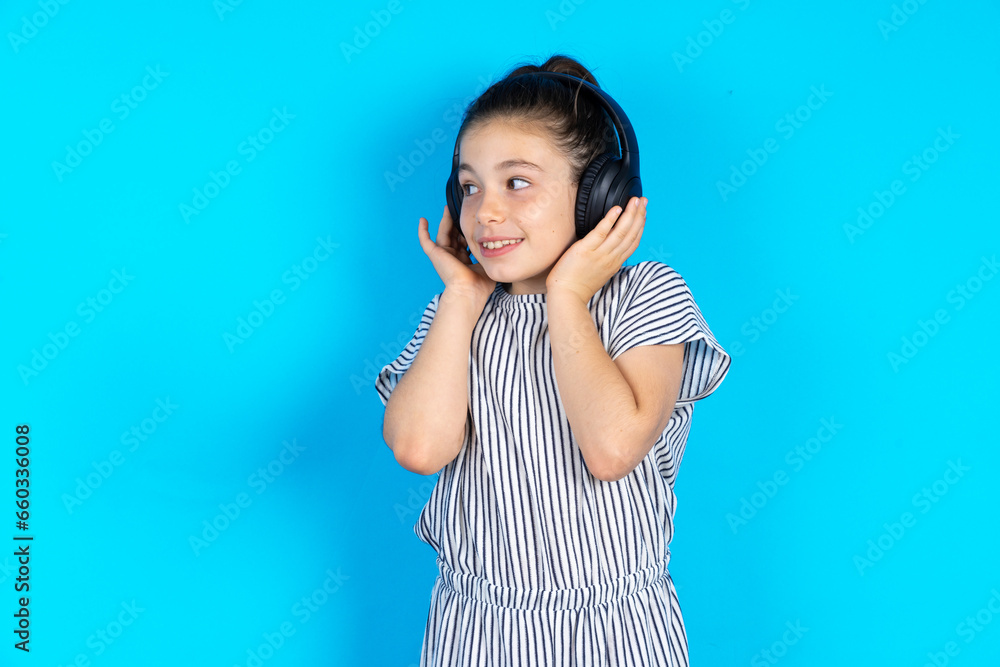 Φωτογραφία Beautiful caucasian kid girl wears stereo headphones listens music concentrated aside