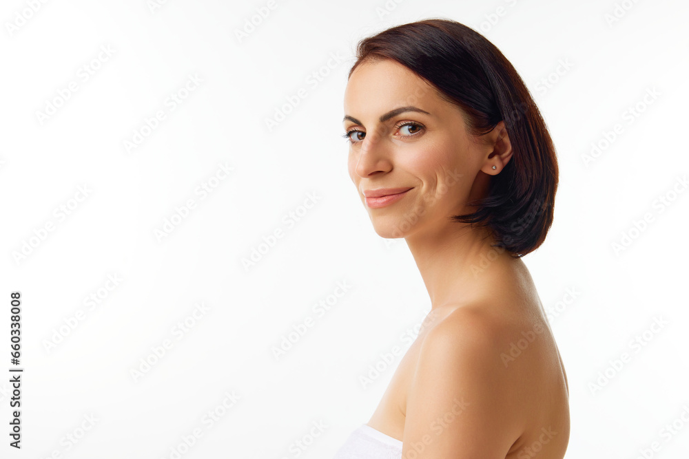 Side view portrait of young smiling woman with naked shoulders and natural facial makeup looking at camera. Beauty face, clean, fresh, smooth skin. Side view portrait of young smiling woman with naked shoulders and natural facial makeup looking at camera. Beauty face, clean, fresh, smooth skin.