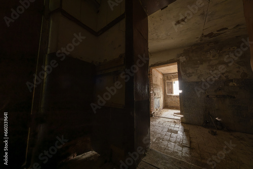 Doorways leading to shabby rooms from grungy corridor inside derelict building in daytime