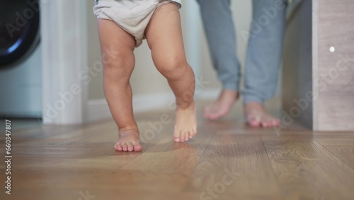baby first steps. happy family a kid dream concept. father teaches baby daughter to take first steps at lifestyle home in front of window. father's day concept. baby takes his first steps