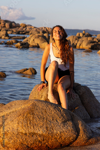 young woman sitting on a rock in the ocean