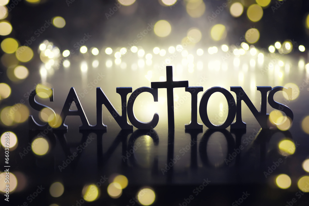 word sanctions spelled in letters on table made of wooden block letters with dramatic lighting and smoke - obrazy, fototapety, plakaty 