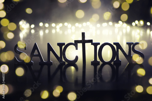 word sanctions spelled in letters on table made of wooden block letters with dramatic lighting and smoke photo