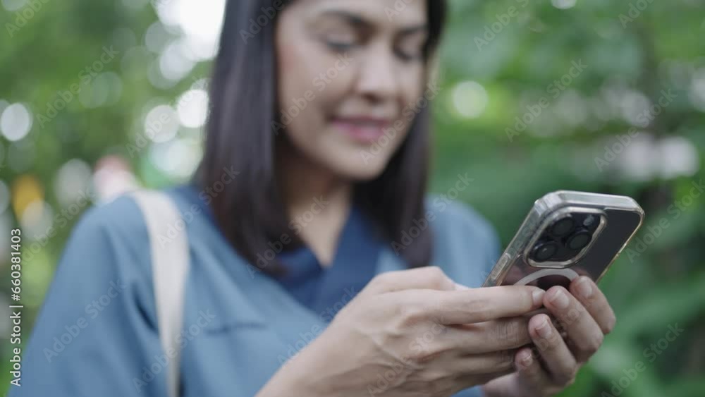 Woman in resort typing message on smartphone standing under palm tree Woman's smartphone surfing the web relaxing on vacation