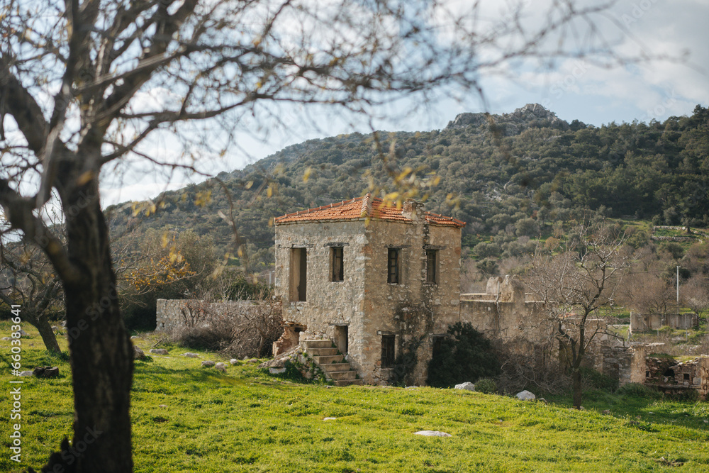 An ancient abandoned two-story stone house in a field with a mountain in the background An ancient abandoned two-story stone house in a field with a mountain in the background