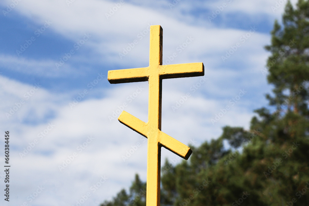 Orthodox cross isolated on sky. Cemetery metal gate cross background. Old, rusty metal faith symbol. East of Poland. Yellow paint metal gate. Orthodox forest graveyard. Entrance to cemetery.