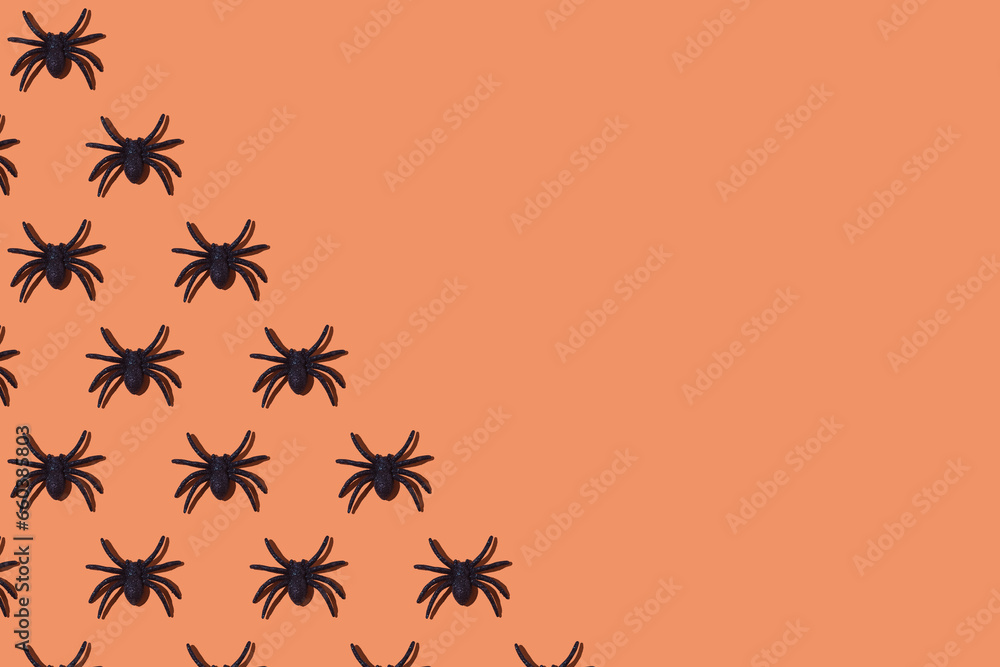 Pattern of shiny plastic spiders as decoration for Halloween, on the left side, on orange background. Concept of terror, phobia, fear, celebration, arachnophobia, day of the dead, repellent and toy. Pattern of shiny plastic spiders as decoration for Halloween, on the left side, on orange background. Concept of terror, phobia, fear, celebration, arachnophobia, day of the dead, repellent and toy.