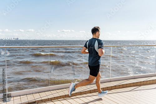 An active lifestyle runner instructor uses a T-shirt and shorts. Warm-up for an active day workout outside the street. Fitness man intensive exercises.