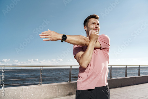 A young man trains in sportswear. Fitness exercises, uses a running app. Portrait of a man using a sports watch.