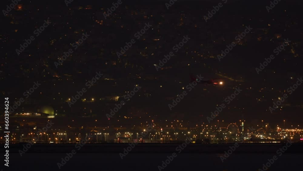 Plane landing against night city backdrop Plane landing against night city backdrop