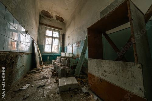 Interior of grungy room with weathered concrete steps and broken tiles on walls inside derelict building