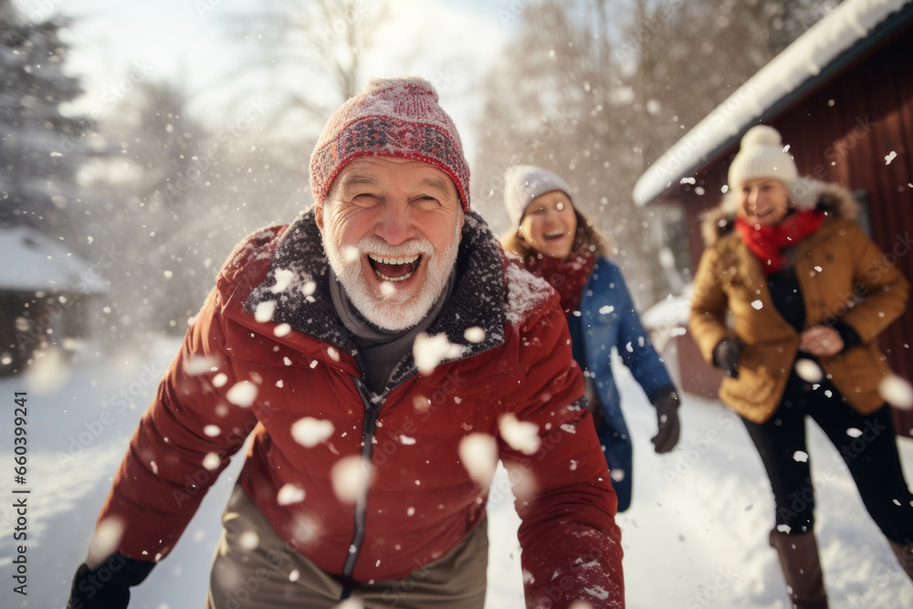 Portrait of happy senior man in winter during snow having fun with family outdoors playing snowballs fight. Active healthy lifestyle in retirement Portrait of happy senior man in winter during snow having fun with family outdoors playing snowballs fight. Active healthy lifestyle in retirement