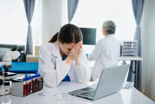 Confident young Caucasian female doctor in white medical uniform sit at desk working on computer. Smiling use laptop write in medical journal