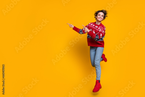 Full length photo of nice girl dressed red jumper flying indicating at christmas offer empty space isolated on yellow color background