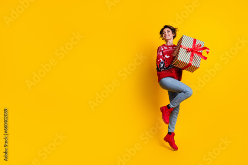 Full size photo of adorable girl dressed ornament jumper hold christmas gift look at sale empty space isolated on yellow color background