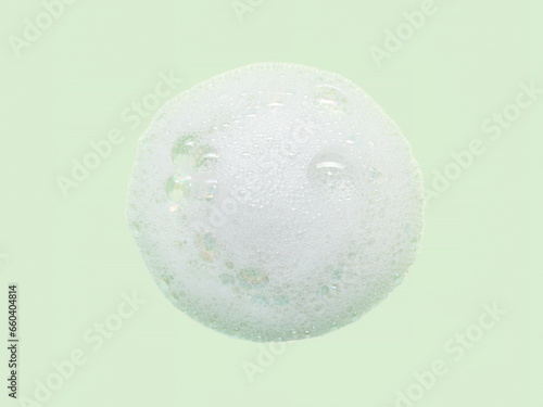 Skincare cleanser foam texture with bubbles isolated on green background. Soap shampoo face wash cleansing musse product sample