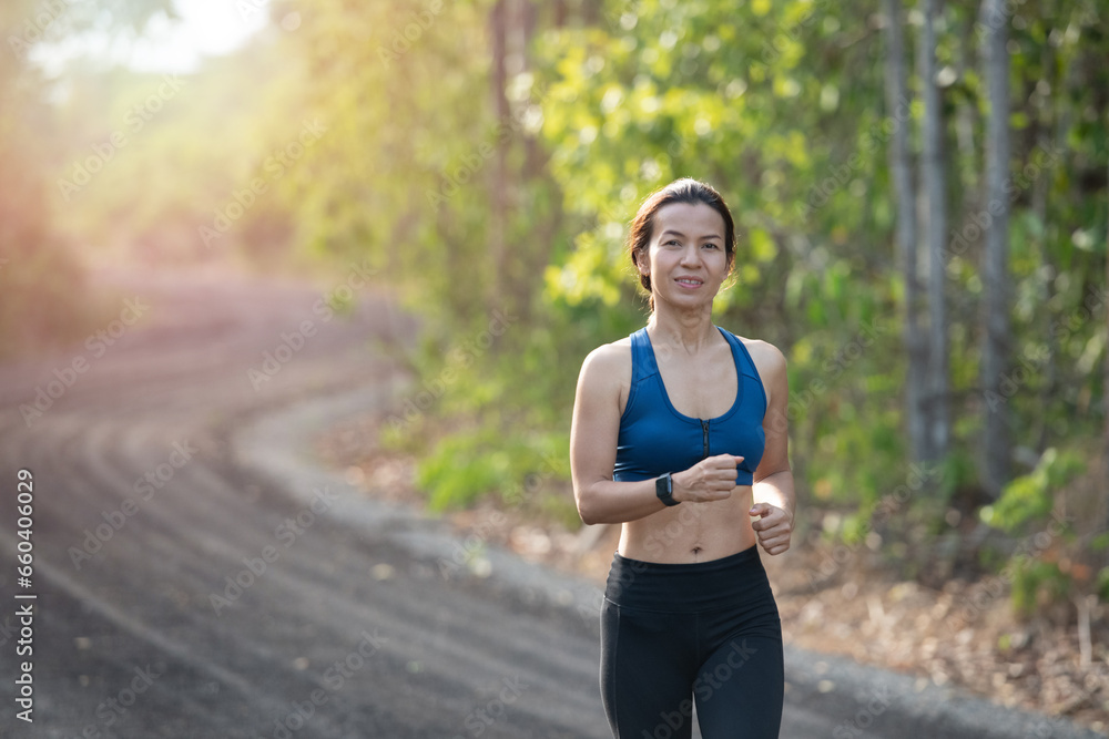 young fitness woman runner athlete running at road. athlete woman in running start pose on countryside street. sport tight clothes. bright sunset, Healthy woman on morning road workout jogging. young fitness woman runner athlete running at road. athlete woman in running start pose on countryside street. sport tight clothes. bright sunset, Healthy woman on morning road workout jogging.