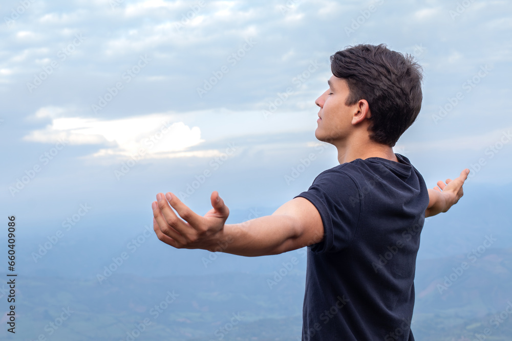 Young Man Breathing Fresh Air and Embracing the Majesty of Nature with Outstretched Arms Young Man Breathing Fresh Air and Embracing the Majesty of Nature with Outstretched Arms