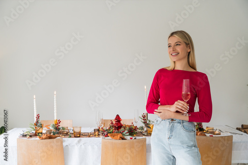 A young woman with glass of shampagne to the camera. Preparing for a festive dinner with friends.  photo