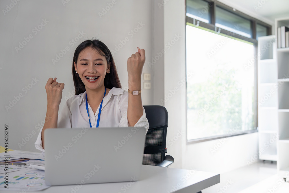 Happy excited successful Asian businesswoman triumph with a laptop computer in the workplace office Happy excited successful Asian businesswoman triumph with a laptop computer in the workplace office