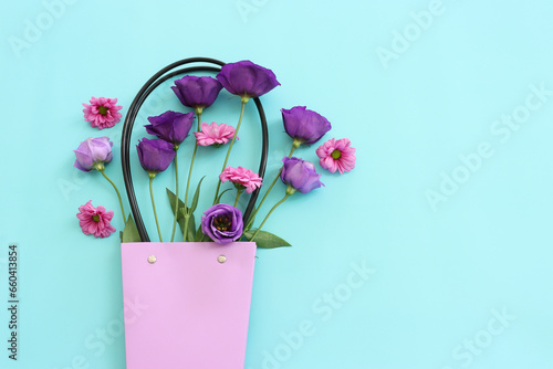 Top view image of pink and purple flowers composition over pastel blue background .Flat lay