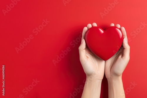 hand holds a red heart love shape on a red background with copy space