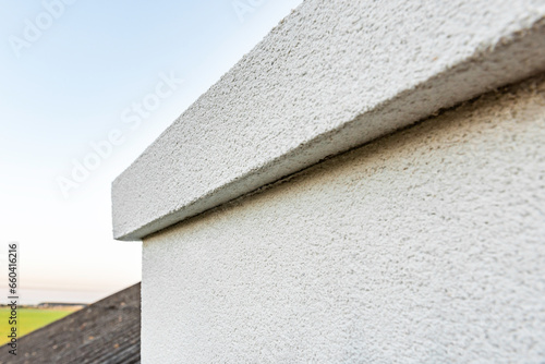 Applying white seamless concrete pebble-dash plaster on chimney. photo