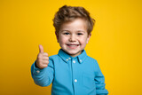 Young boy giving thumbs up sign with his hand.