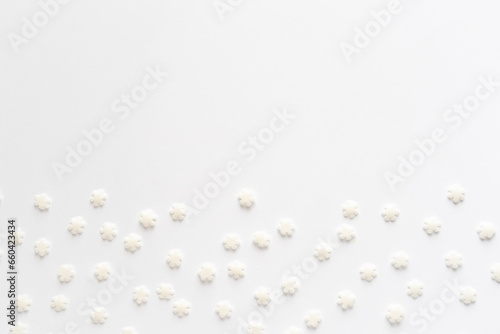 White sugar sweet snowflakes sprinkles on white background. Sweet backing decoration for cake and candy.Copy space. 