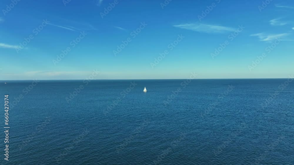 Aerial view of a sailing boat navigating in the middle of the sea under the blue sky on a sunny day Aerial view of a sailing boat navigating in the middle of the sea under the blue sky on a sunny day