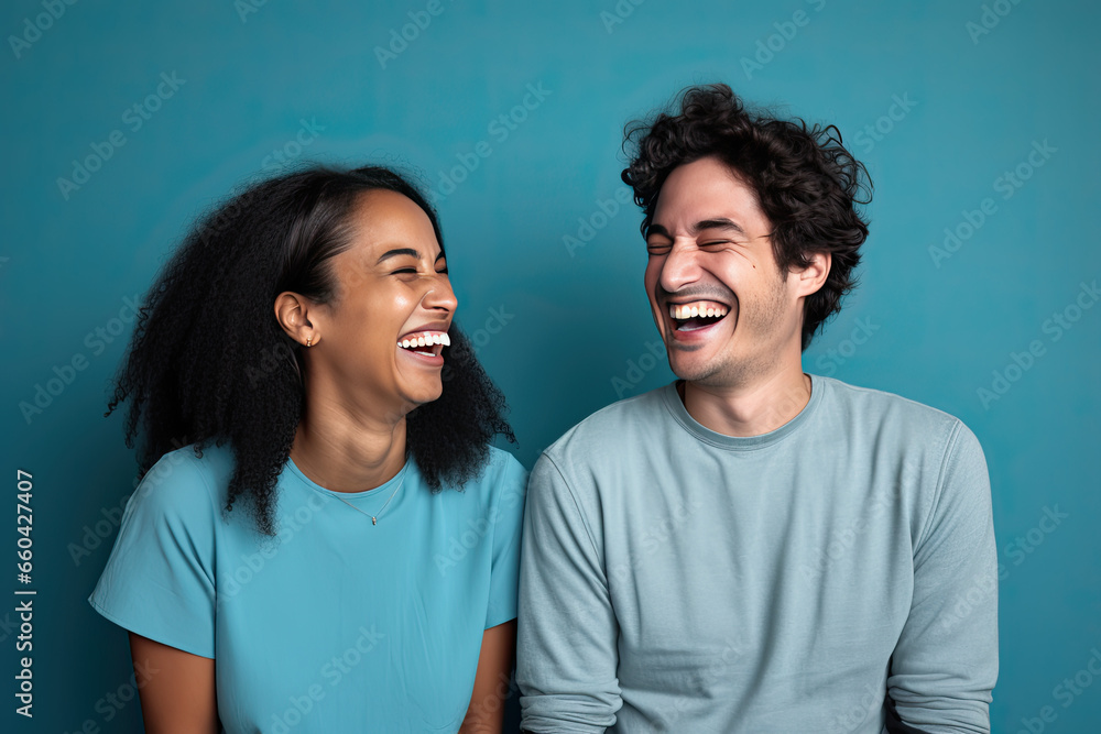 Obraz premium Funny couple laughing cheerfully while sitting together in a studio