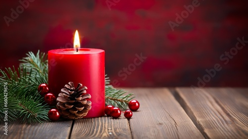 A christmas candle with christmas decorations on a wooden table against a dark red background