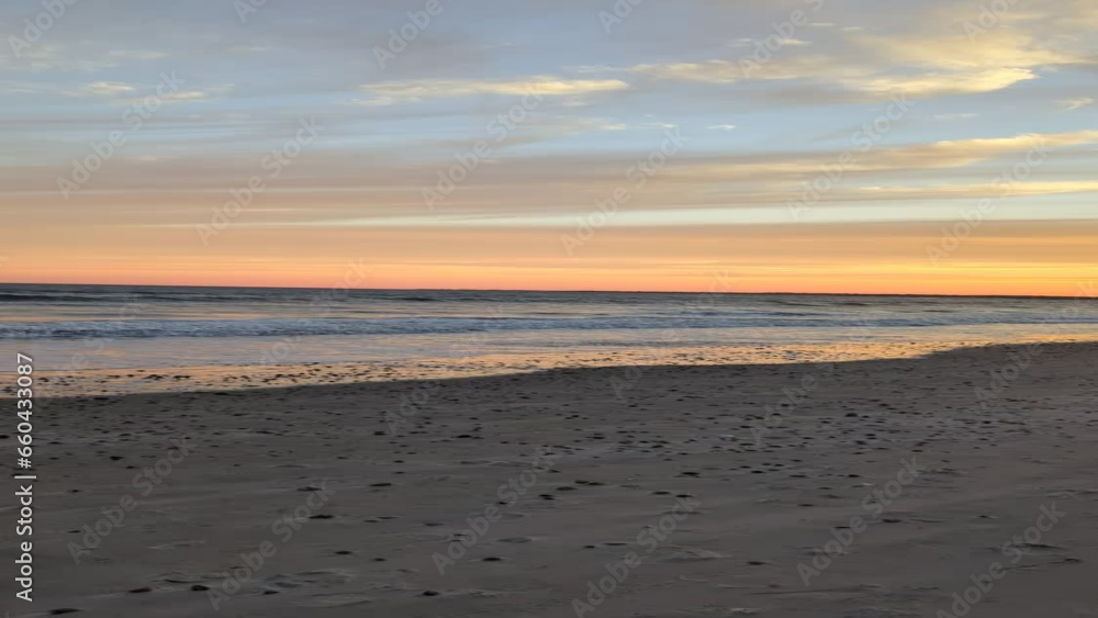 Landscape view of the sea waves on a sandy beach with colorful dusk sky in the background at sunset Landscape view of the sea waves on a sandy beach with colorful dusk sky in the background at sunset