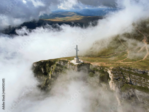 Aerial view of the Heroes' Cross monument, built to honor the Romanian soldiers fallen during WWI. The cross sits on the small summit of the Caraiman Peak, overlooking the town of Bușteni in Romania. photo