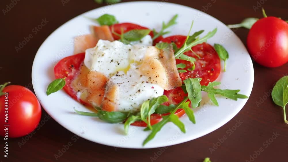 Cooked poached egg with herbs, lightly salted salmon and tomatoes with spices on a wooden table. Cooked poached egg with herbs, lightly salted salmon and tomatoes with spices on a wooden table.