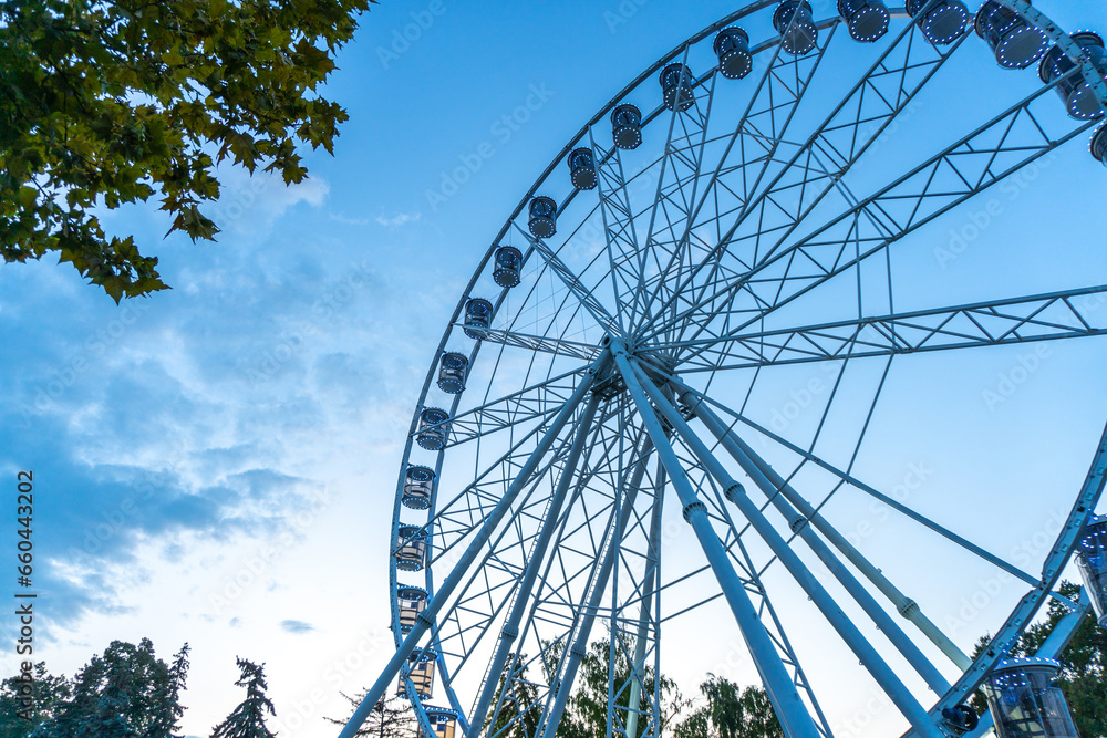 Big, tall white Ferris wheel in front of a perfect blue sky Big, tall white Ferris wheel in front of a perfect blue sky