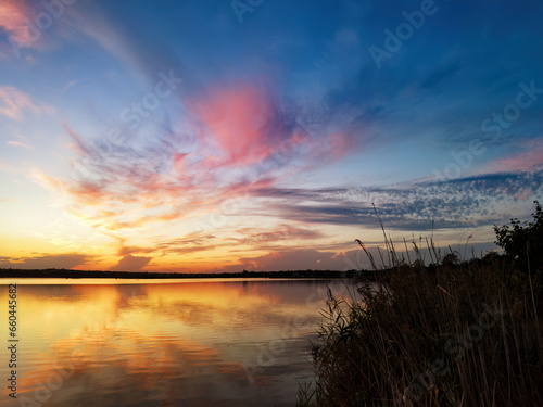 Vibrant sky reflecting on a calm and serene lake © pobaralia