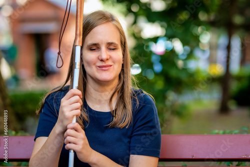 Wallpaper Mural A visually impaired woman holding a white cane and sitting on the bench on the city park Torontodigital.ca