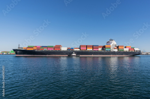 View of freight container cargo ship with tug boat in Los Angeles California.